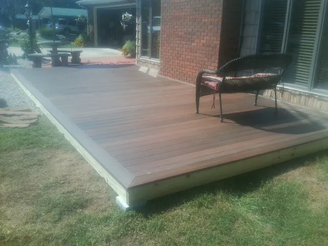 New wood deck and wicker chair beside a brick house in Hopkins