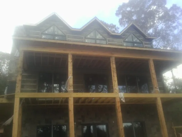 Dormers and porch framing on a large log home under construction — Roof Coating work by our crew in Hopkins