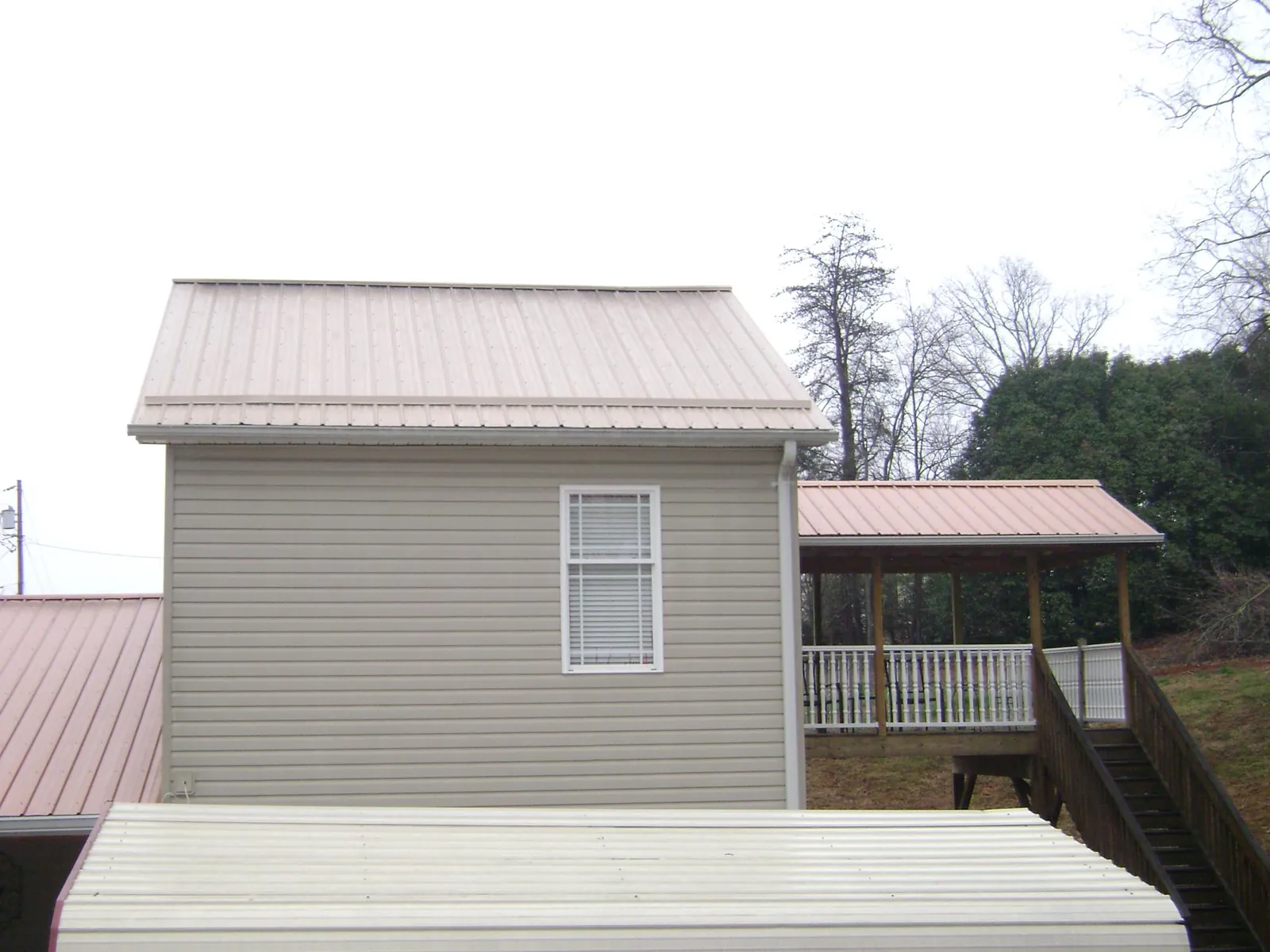 Tan metal roofs on a two story addition and attached porch, from a Roof Replacement job in Hopkins